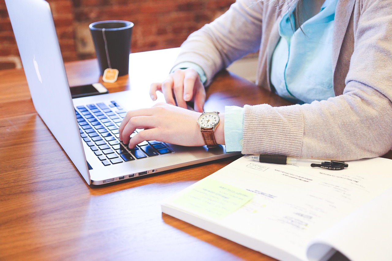Person typing an email on a laptop while an AI chat interface suggests a reply